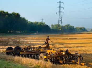 Electricity pylon and farm machinery in a Radley field at dawn