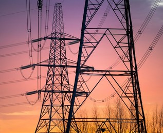 Giant pylons on Kennington Meadows, glowing scarlet winter sunrise