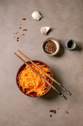 Dish of the rean and Asian Cuisine: Vegetable Salad Marinated Carrots with Garlic. Served In Ceramic Bowl with Chopsticks. Seasoning In Small Bowls on Mocha Mousse Tones Table. Healthy Eating. Top View