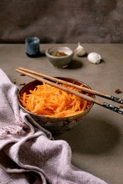 Dish of the rean and Asian Cuisine: Vegetable Salad Marinated Carrots with Garlic. Served In Ceramic Bowl with Chopsticks. Seasoning In Small Bowls on Mocha Mousse Tones Table. Healthy Eating.