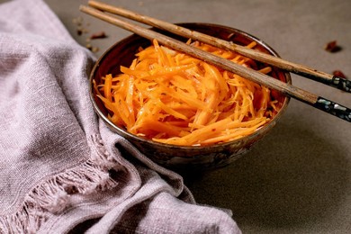 Dish of the rean and Asian Cuisine: Vegetable Salad Marinated Carrots with Garlic. Served In Ceramic Bowl with Chopsticks. Seasoning In Small Bowls on Mocha Mousse Tones Table. Healthy Eating.