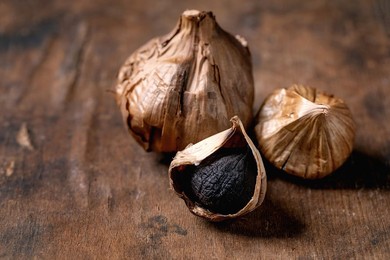 Black Fermented Garlic Whole and Peeled Garlic Clove On Dark Wooden Table. Healthy Eating. Spicy Cooking Ingredients. Asian Kitchen