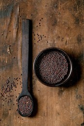 Black Mustard Seeds For Cooking Dijon Mustard In Black Ceramic Bowl with Spoon On Dark Wooden Table. Healthy Eating. Spicy Cooking Ingredients. Traditional Kitchen. Top View