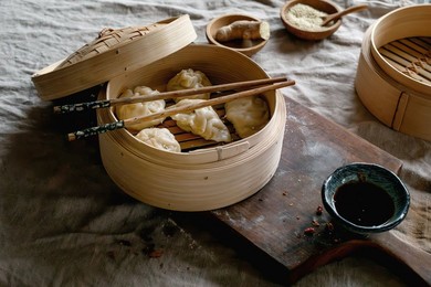 Bamboo Steamer with Asian Steamed Dumplings. Chopsticks. Soy Sauce On Wooden Board On Rustic Wooden Table. Natural Daylight. Asian Food