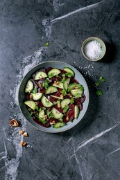 Vegan Beet Salad. Marinated Sliced Beetroot With Fresh Cucumber. Walnuts. and Coriander Leaves In Ceramic Bowl. Nearby Bowl With Sea Salt On Black Marble Table. Healthy. Plant-based Dish. Top View