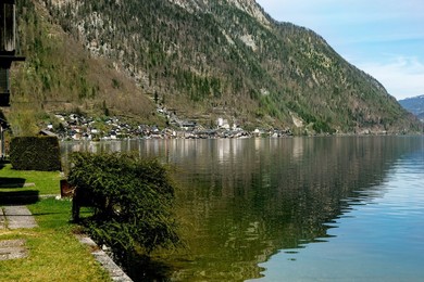 Hallstatt Austria. Picturesque Village Surrounded by Mountains on Shores of Calm Lake. Green Hillside with Reflection In Clear Water. Idyllic European Alpine Landscape Perfect For Travel Destination