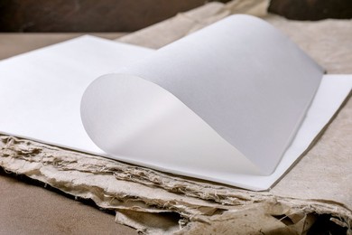 Closeup Blank White Rice And Mulberry Paper Sheet with Curled Page on Recycled Cardboard Background. Minimalist Composition with Clean Paper And Textured Ecofriendly Materials