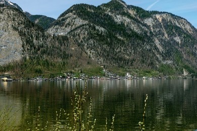 Hallstatt Austria. Scenic Mountain Lake Landscape with Small Village Along Shore. Majestic Forested Mountains Towering Behind Settlement Calm Water Reflecting Surrounding Nature