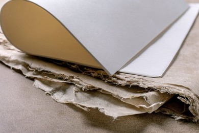 Close Up White Rice And Mulberry Paper Sheets Placed on Textured Handmade Paper Background. Natural Materials Workspace Composition. Art Supplies For Creative Work