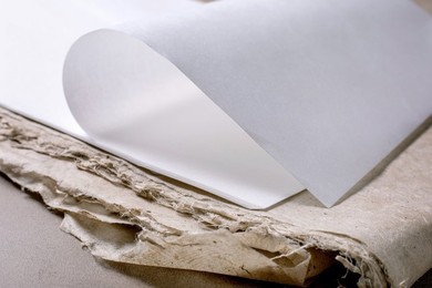 Clean White Rice And Mulberry Paper Sheet Placed on Textured Handmade Paper with Rough Edges. Minimalist Composition Highlighting Contrast Between Smooth Modern And Rustic Traditional Papermaking