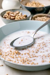 Closeup of Creamy Sprouted Wheat Porridge with Wheat Grains Spoon. Blue Ceramic Bowls with Various Nuts Seeds Background. Healthy Breakfast Concept