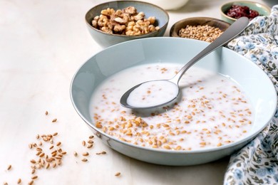 Bowl of Sprouted Wheat with Milk with Grains Spoon. Small Bowls of Walnuts Seeds And Dried Berries. Healthy Breakfast Concept Clean Eating Nutritious Meal
