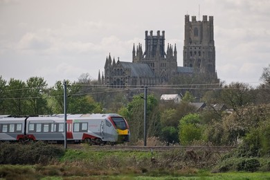 Greater Anglia train passing in front of the Ely Cathedral , Ely, Cambridgeshire, UK.