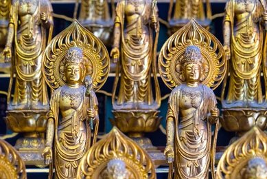 Golden Buddha statues with ornate aureoles and lotus thrones displayed on Buddhist altar in temple in Nagoya, Japan showing religious artistry